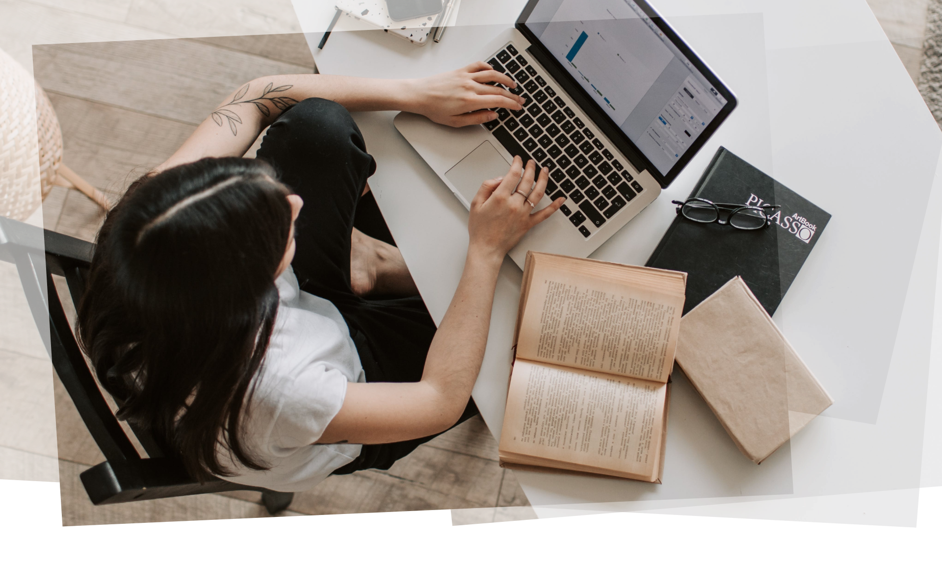 Aerial view of a woman sitting at a desk working on her laptop with books on the desk next to her