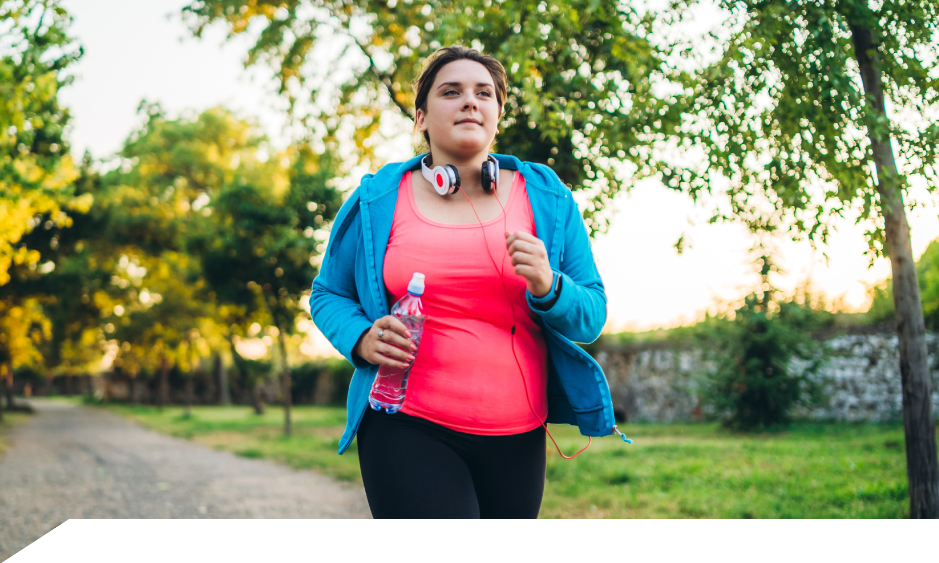 A woman walking in a park wearing workout clothes