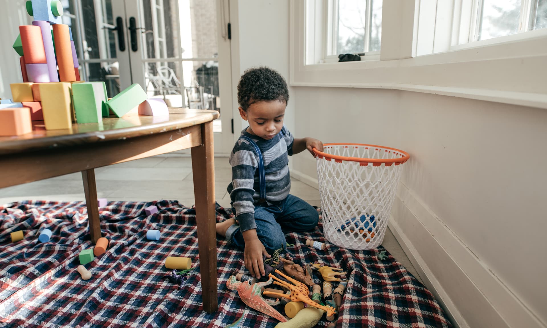 little kid putting toys away