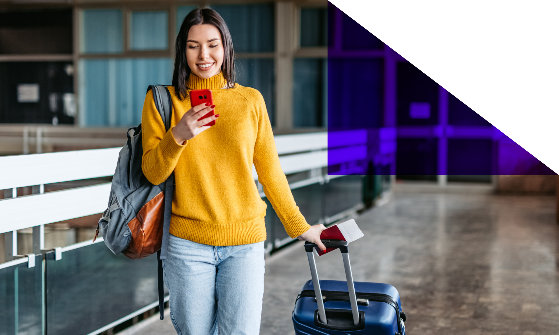 woman with suitcase and backpack checking phone while walking in airport