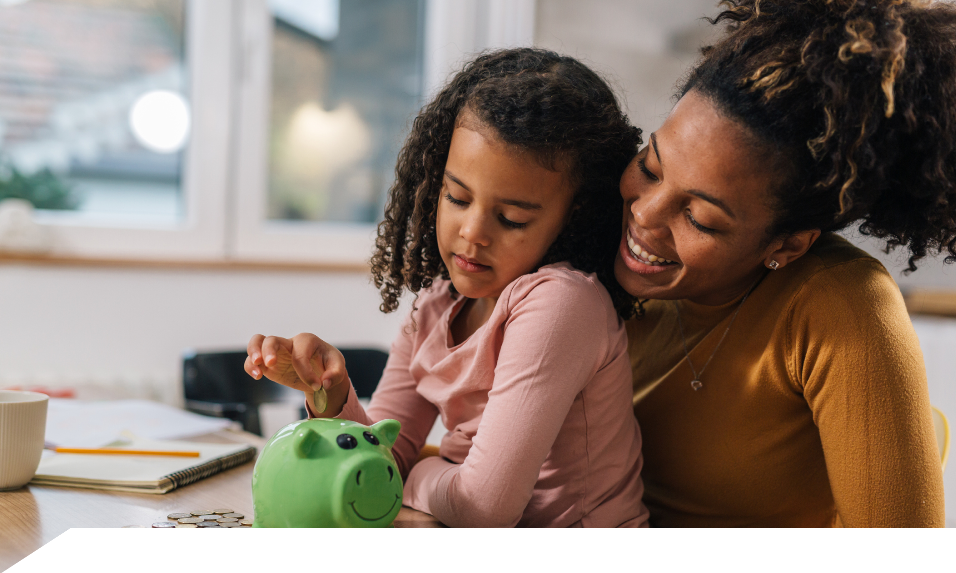 mom and daughter putting money in piggy bank