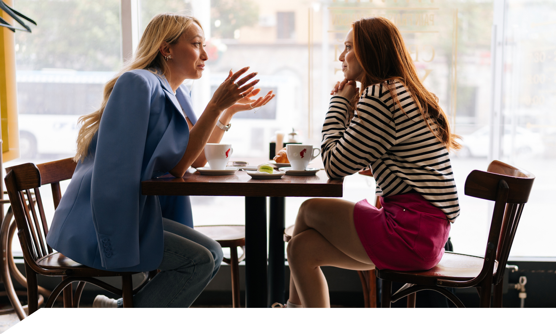 Two women talking, sitting at a coffee shop