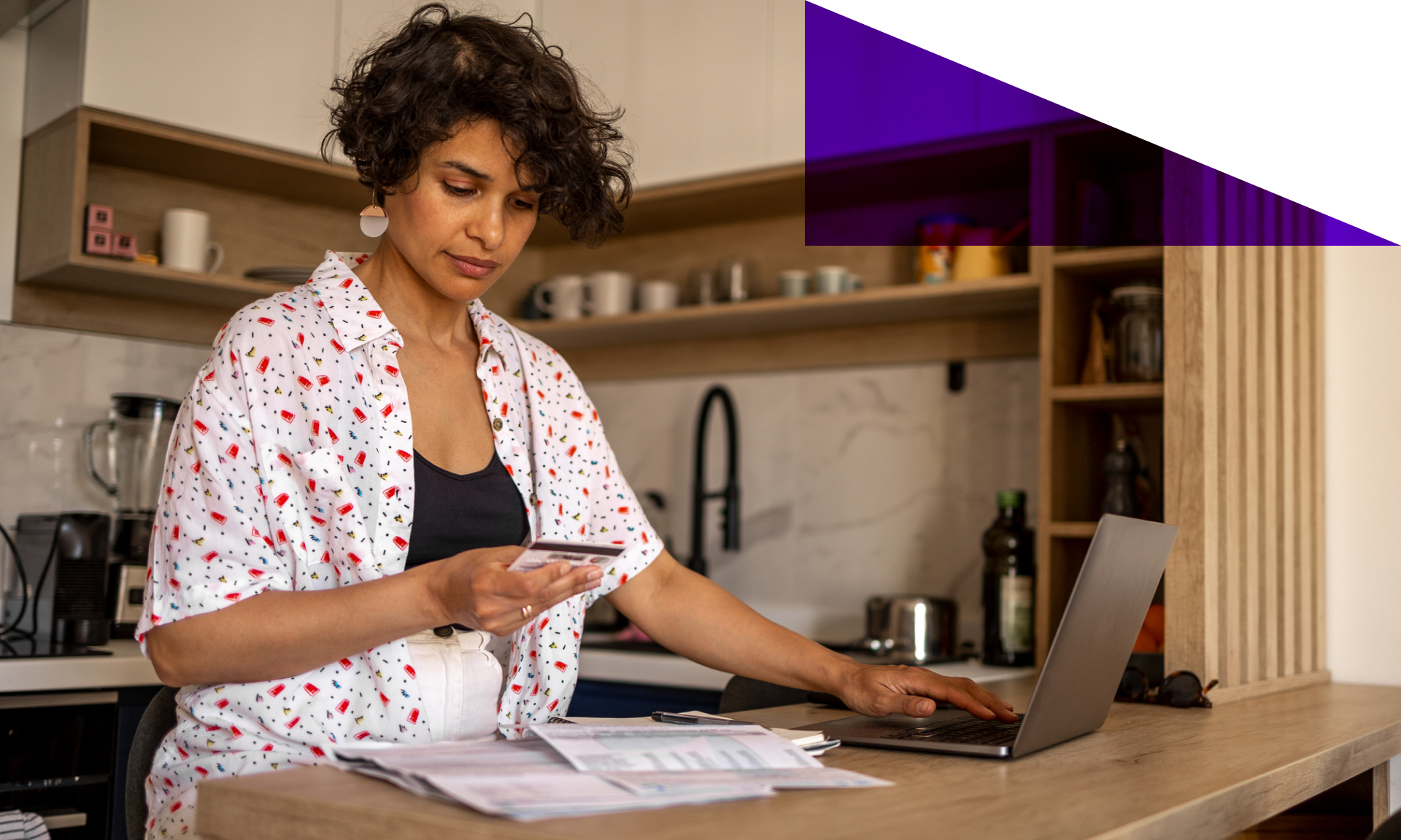 Woman standing at her kitchen counter inputting her credit card information on her laptop.