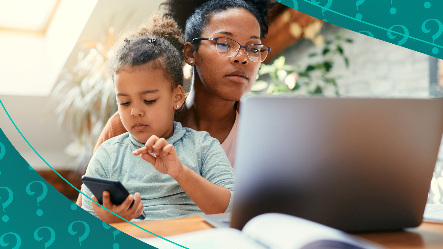 Woman holds child and works on laptop