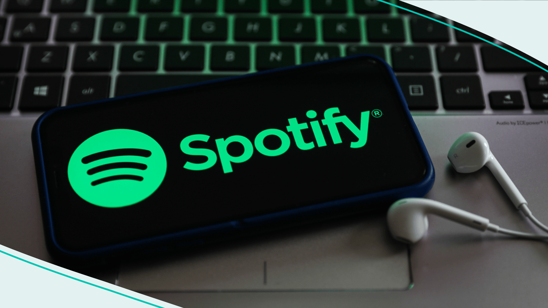 Spotify logo displayed on a phone screen, keyboard and headphones