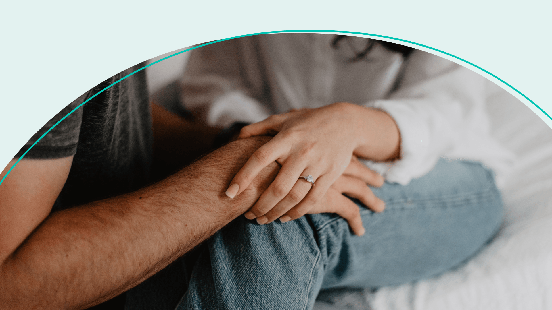 A man sitting in front of each other with his hand on a woman's knee and the woman's hand on his hand
