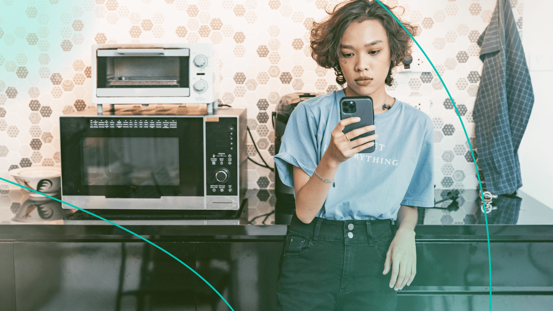 Woman looking at phone in the kitchen next to microwave