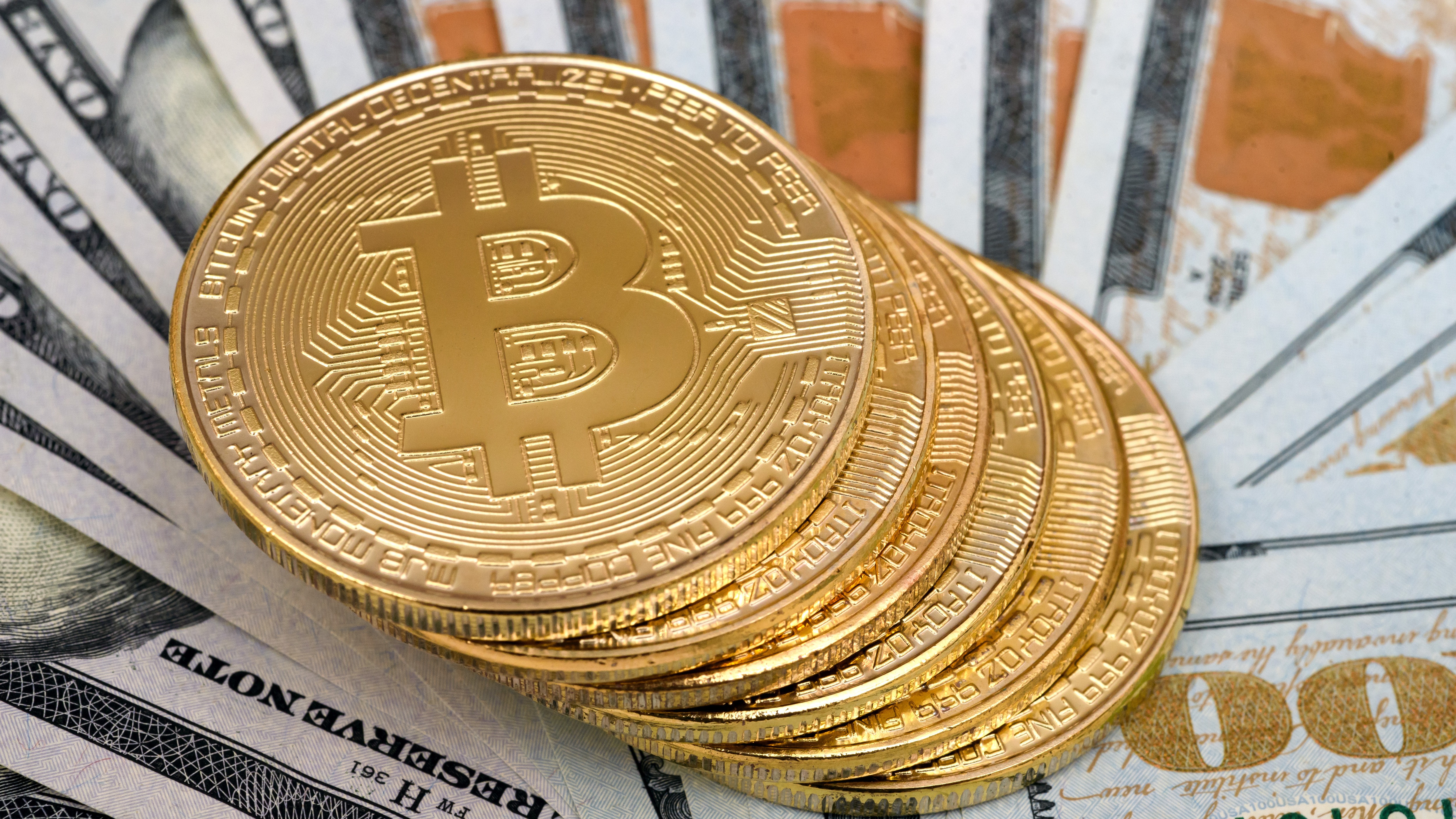 Bitcoin cryptocurrency commemorative coins seen on top of the US dollars.