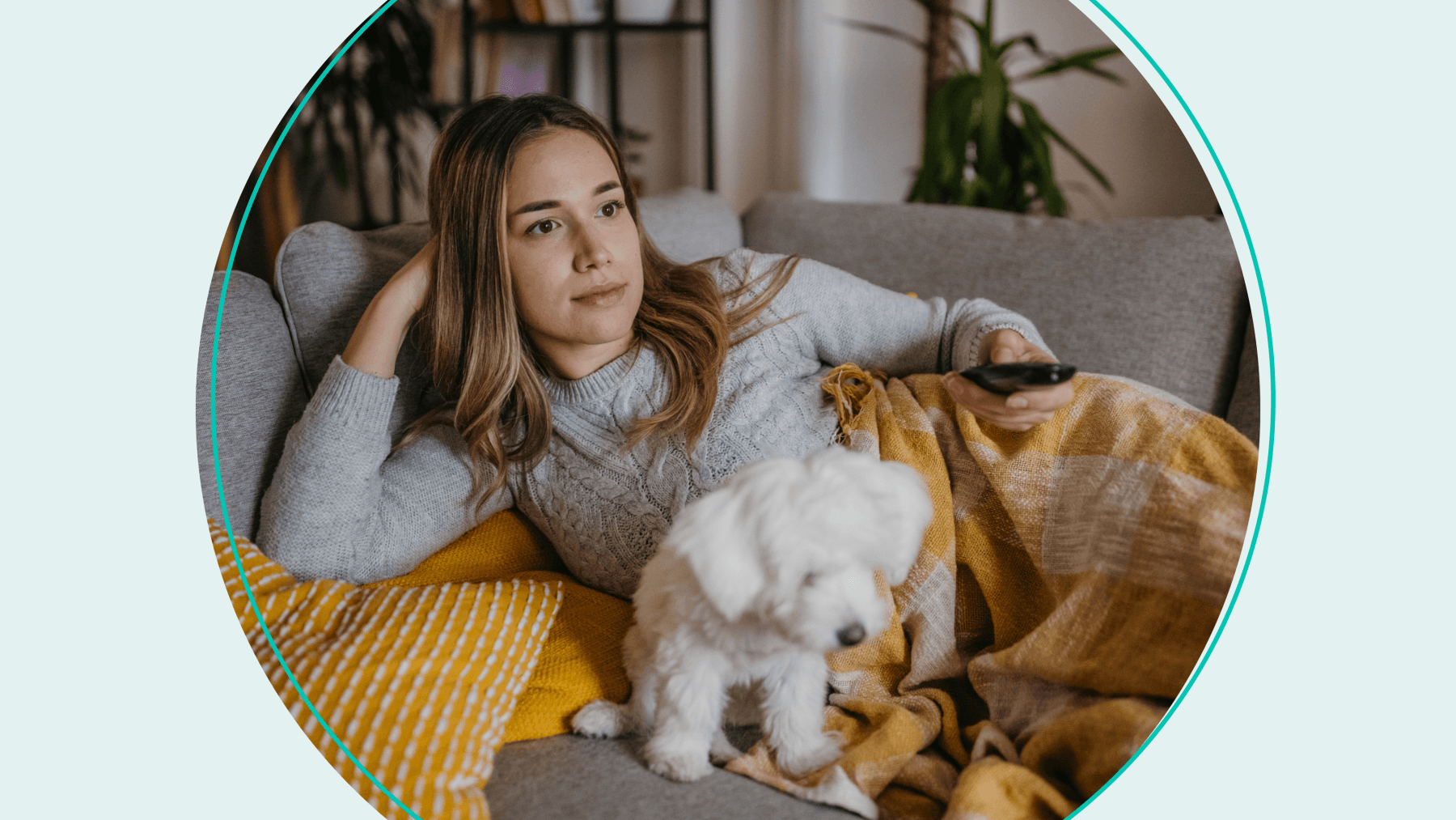 Woman on couch, under a blanket, with a dog