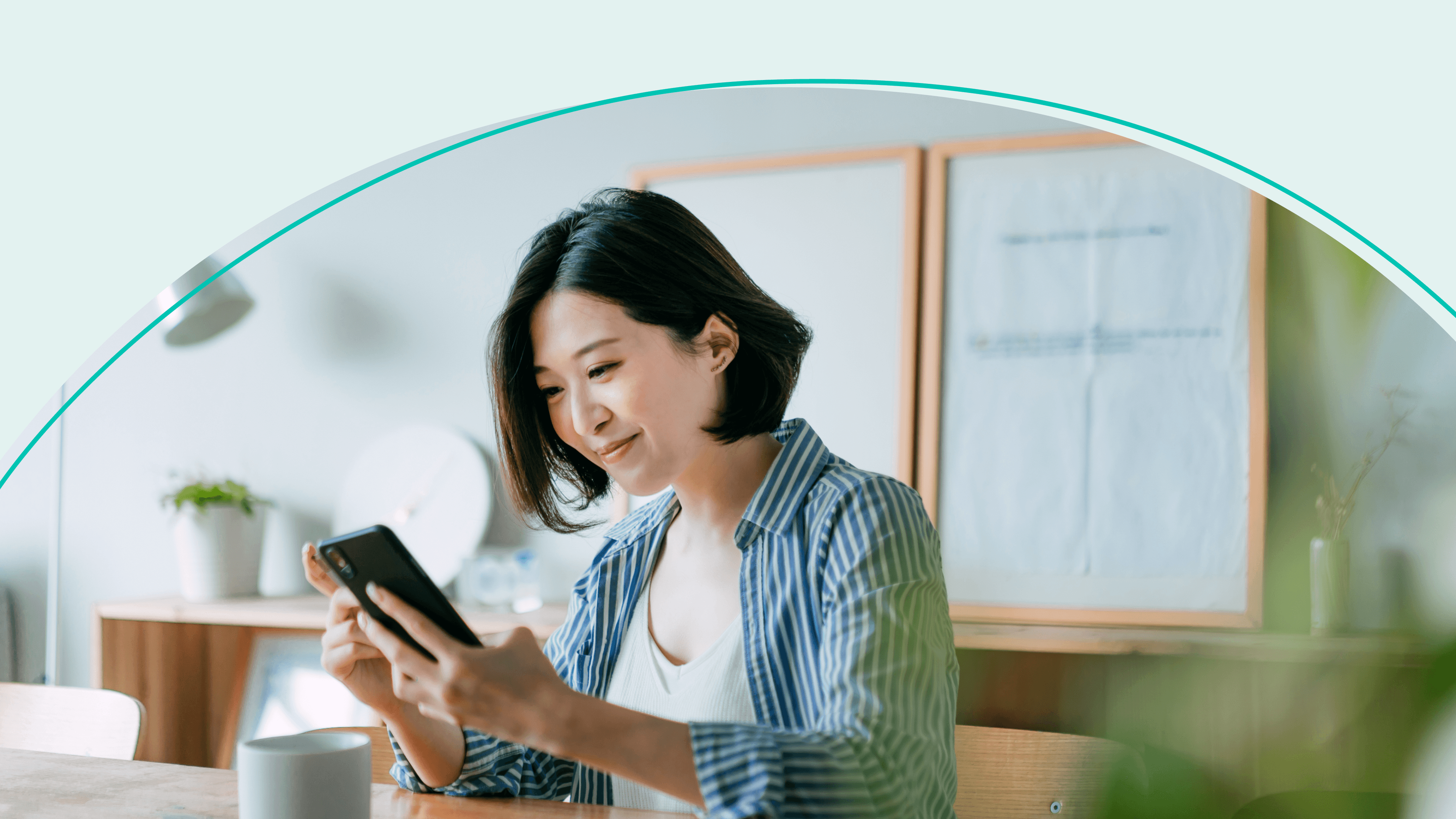 woman sitting at a table and smiling at her phone