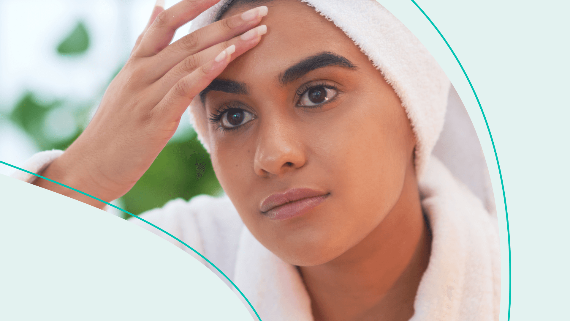 A person with a towel around their hair looking in the mirror touching their face