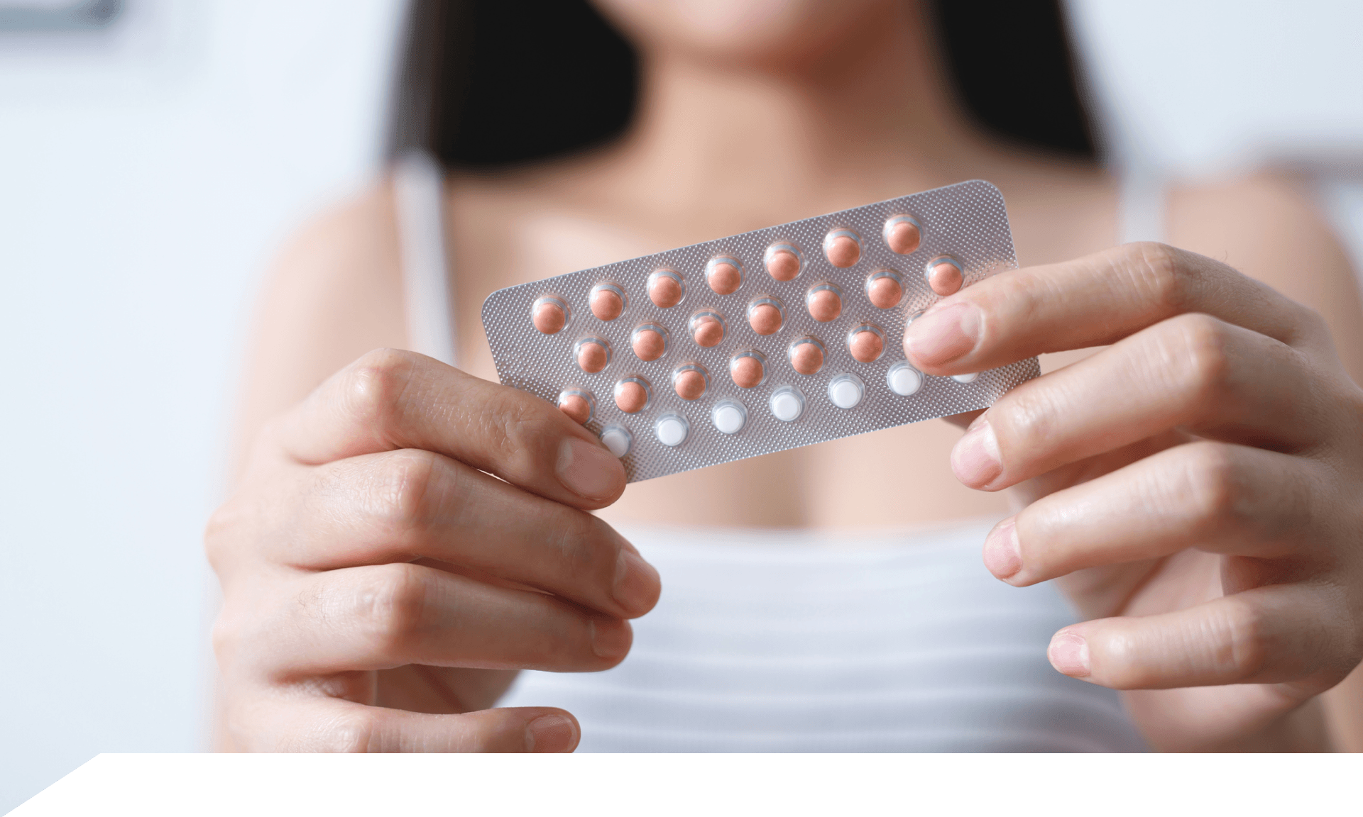 A woman holding up a birth control pill packet