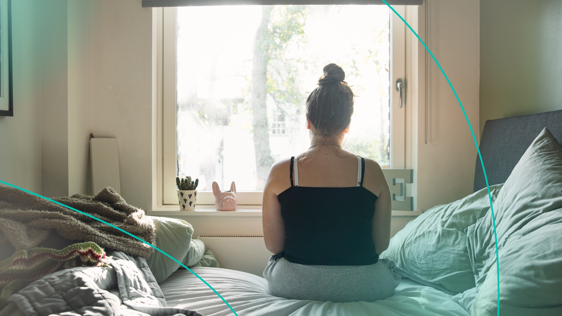 Woman looking out window sitting on bed