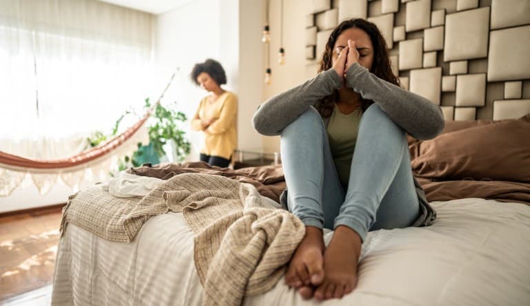 Worried young woman sitting on bed in the bedroom at home. This photo is being used to promote an article answering the question