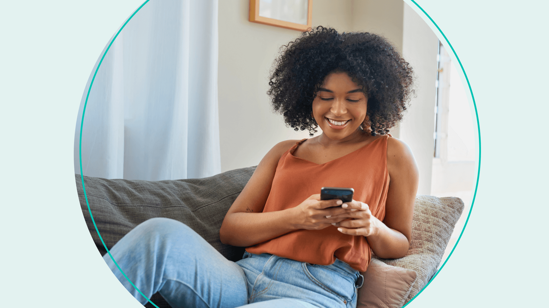 woman on couch smiling using her phone
